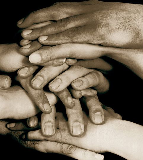 Hands stacked on top of one another on conference table, Sepia,